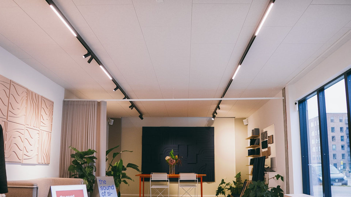 Akustikpaneler monteret i fuldt dækkende loft med integreret skinnebelysning i ARKU showroom